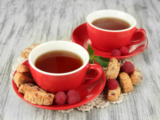 Cups of tea with cookies and raspberries on table close-up