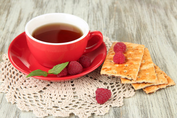 Cup of tea with cookies and raspberries on table close-up