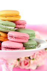 Gentle macaroons in vase on table on light background