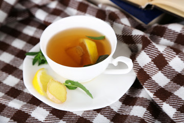 Cup of tea with ginger on plaid with a book