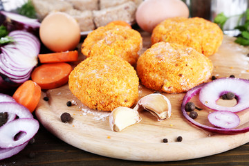 Meat patties on board on wooden table