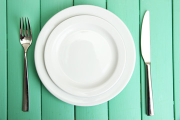 Plate and cutlery on wooden table close-up