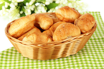 Tasty croissants in wicker basket on table on white background