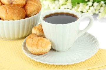 Tasty croissants and cup of coffee on table on white background