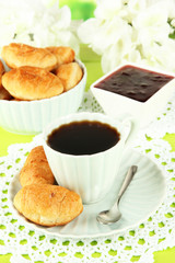 Tasty croissants and cup of coffee on table close-up