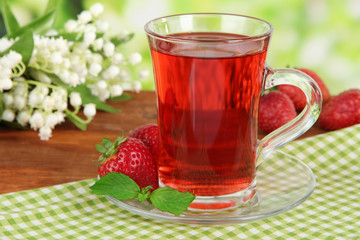 Delicious strawberry tea on table on bright background