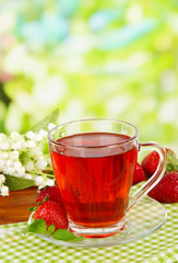Delicious strawberry tea on table on bright background