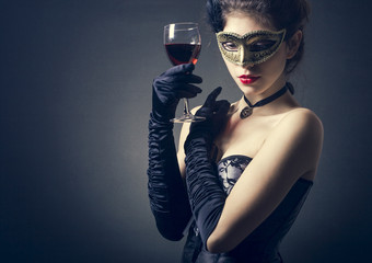 young woman in carnival mask and a glass of red wine.