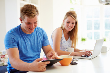 Fototapeta premium Teenagers Having Breakfast Using Laptop And Tablet Computer