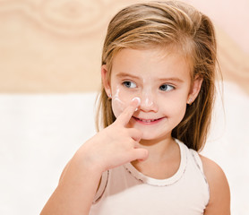 Cute little girl  applying cream