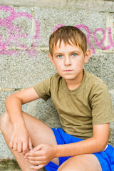 Fototapeta premium Close-up portrait of serious little boy sitting outdoors