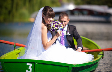 bride holding bouquet while groom is rowing a boat