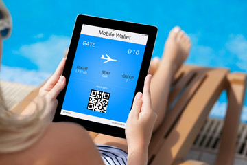 girl lying on a deck chair by the pool and holding a tablet with