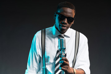 Retro african american jazz singer with microphone. Wearing shir