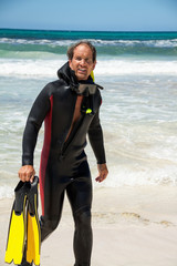 Männlicher Taucher mit Flossen und Neopren Anzug am Strand