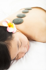 Obraz na płótnie Canvas relaxed woman in spa salon with stones