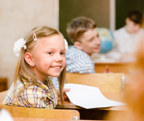 Portrait of schoolgirl at workplace with teacher on background