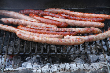 Fresh sausages grilling outdoors on a charcoal barbecue grill
