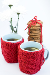 Two blue cups in knitted covers and chocolate cookies