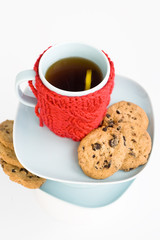 Blue cup with red knitted cover and cookies with chocolate