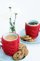 Two blue cups in knitted covers and chocolate cookies