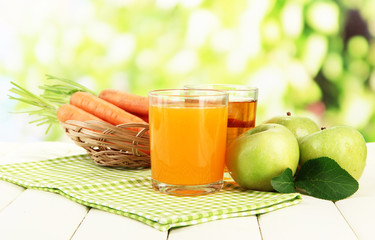 Glasses of juice, apples and carrots