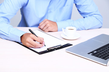 Businessman writing on document in office close-up