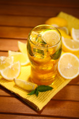 Iced tea with lemon and mint on wooden table