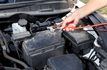 Car mechanic uses battery jumper cables to charge dead battery