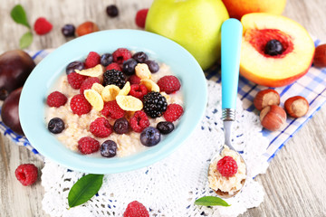 Oatmeal in plate with berries on napkins on wooden table