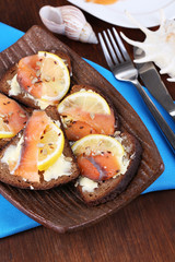 Salmon sandwiches on plate  on wooden table close-up