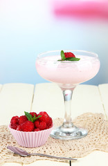 Raspberry milk dessert in cocktail glass, on light background