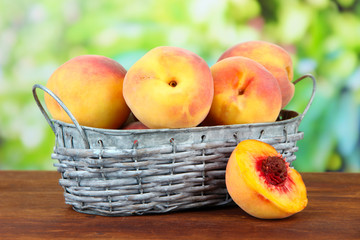 Ripe sweet peaches in wicker basket, on bright background