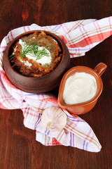 Potato pancakes in pot, on wooden background