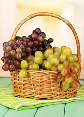 Fresh grape on wicker mat on bright background