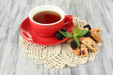 Cup of tea with cookies and blackberry on table close-up