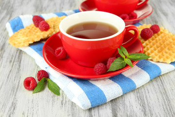 Cups of tea with cookies and raspberries on table close-up
