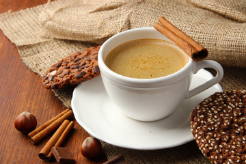 Cup of tasty coffee with tasty cookies, on wooden background