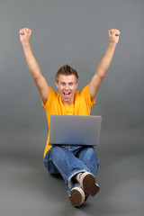 A handsome young man with laptop on grey background