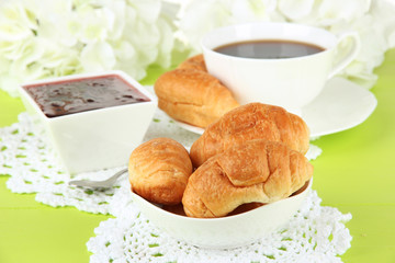 Tasty croissants and cup of coffee on table close-up