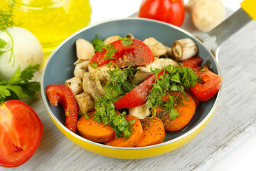 Sliced fresh vegetables in pan on wooden board isolated on