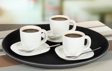 Cups of coffee on tray on table in cafe