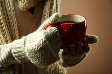 Female hands with hot drink, on color background
