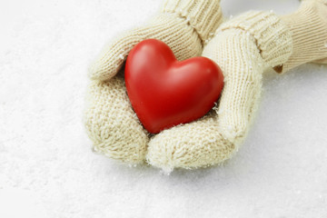 Female hands in mittens with red heart, close-up