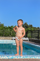 Naklejka premium Little boy standing at the edge of a pool
