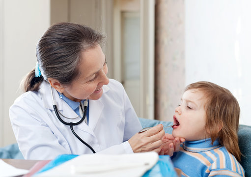 pediatrician doctor looks mouth of baby