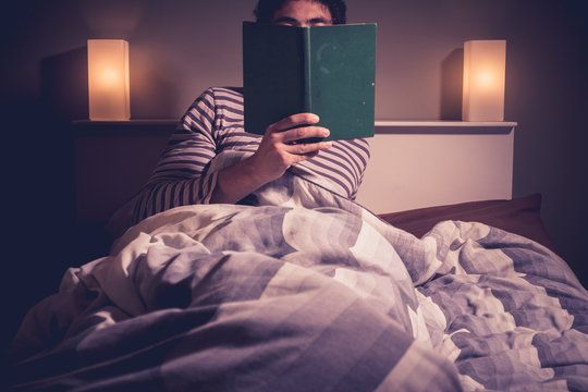 Young man is reading in bed