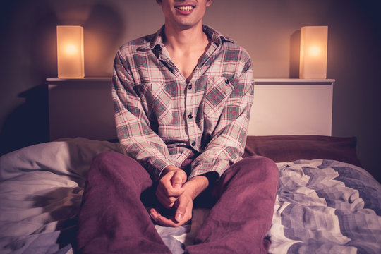 Man sitting on bed in hotel room at night