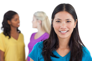 Smiling asian woman looking at camera with two women behind her