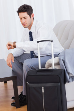 Businessman with his baggage waiting for flight sitting on sofa